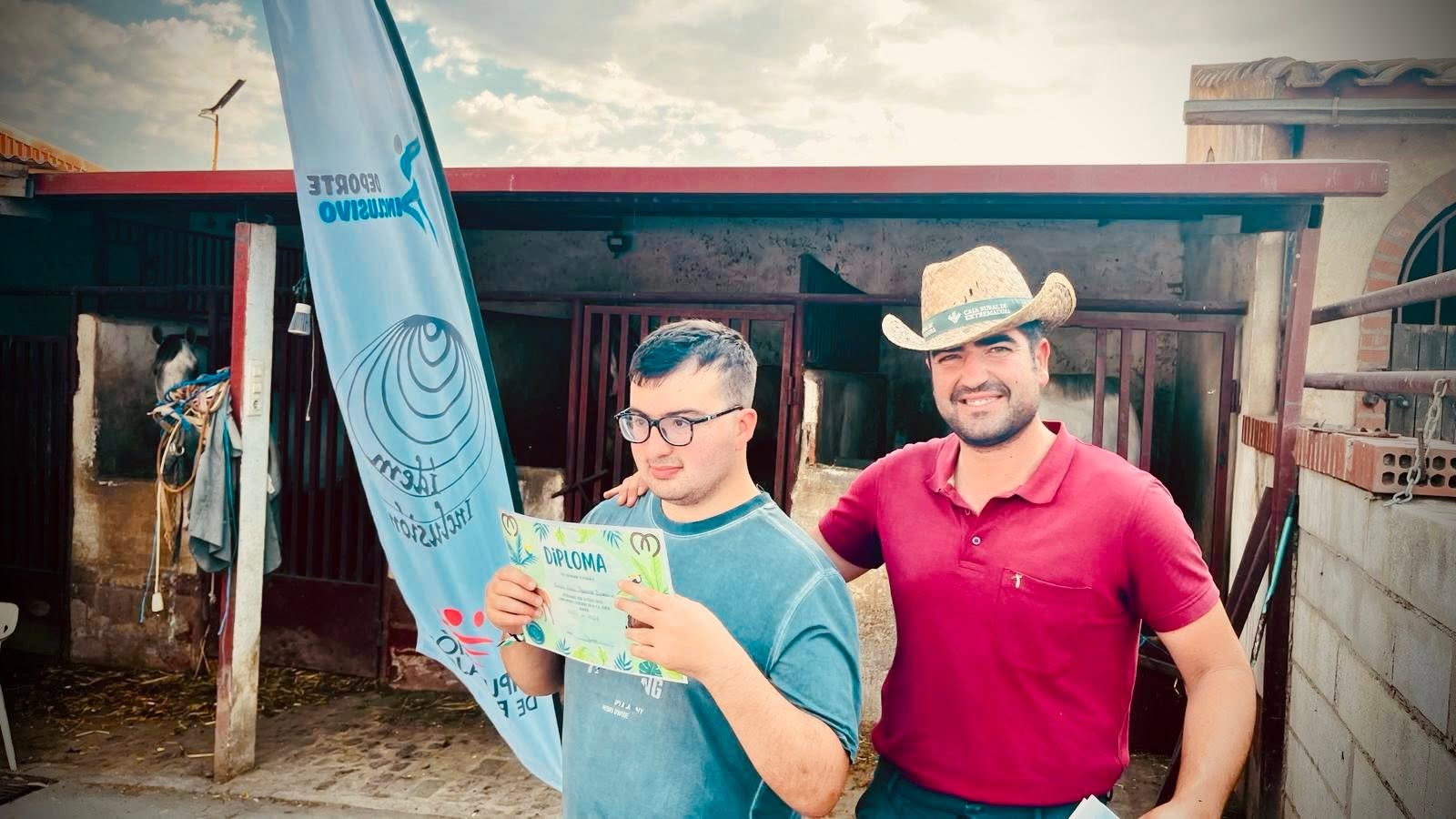 Un participante muestra su diploma junto al profesional de la actividad ecuestre